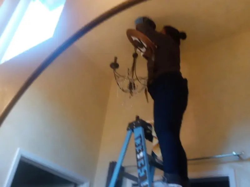 Electrician installing a chandelier in a Augusta residence